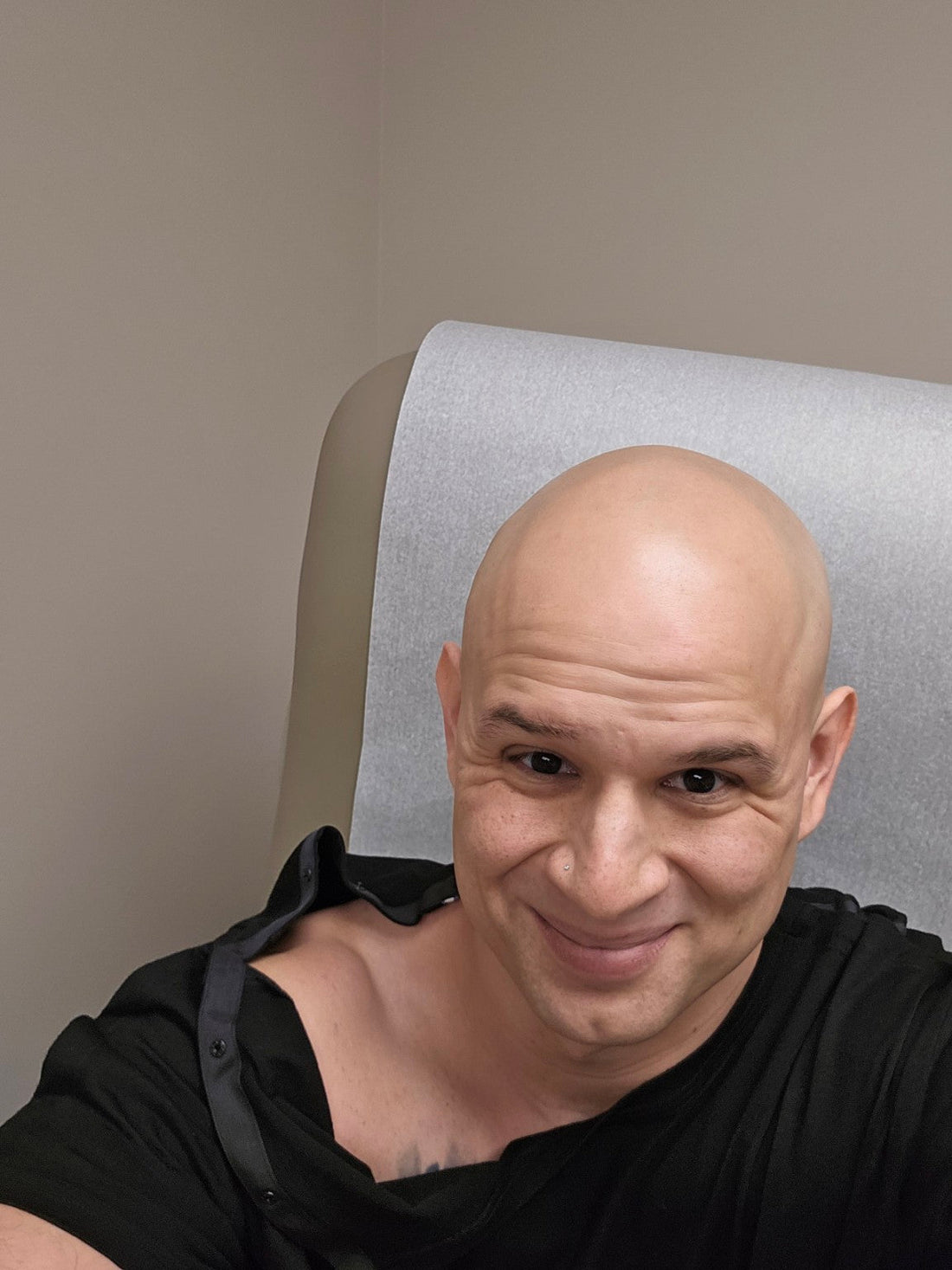 Person wearing a black adaptive shirt while seated in a medical chair