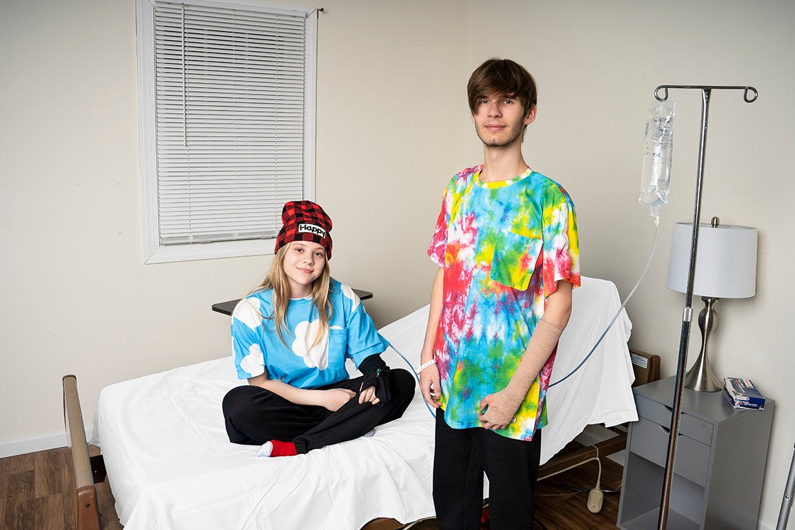 Two people in a room with a bed and medical equipment.