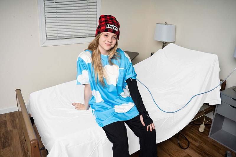 Young woman wearing a black Happy Cloud IV cover with a blue adaptive T-shirt in a treatment room
